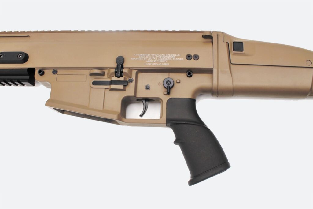 Photorealistic 8K alternative angle view of the SR12 shotgun from the side, placed on a workbench with accessories nearby, highlighting the barrel and Picatinny rails
